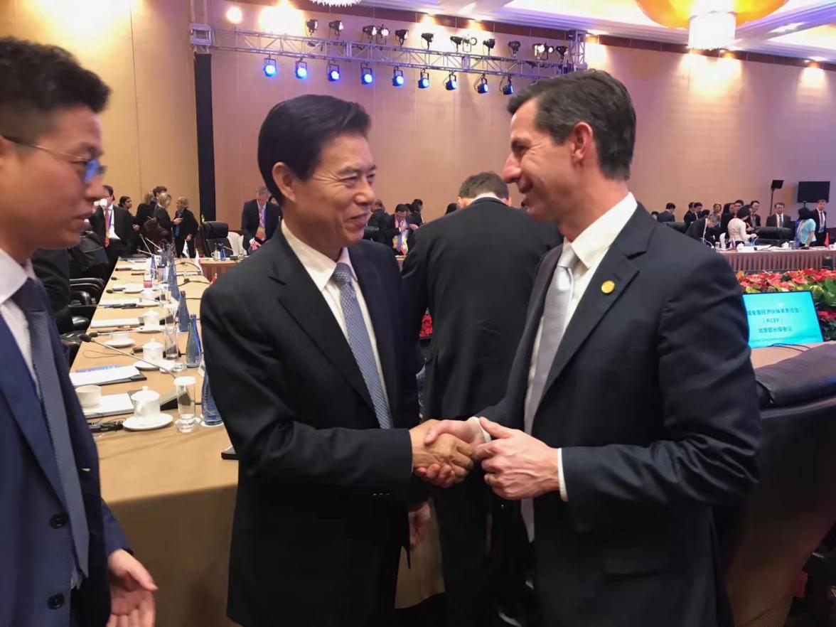 Simon Birmingham shaking hands with Zhong Shan in a function room. 