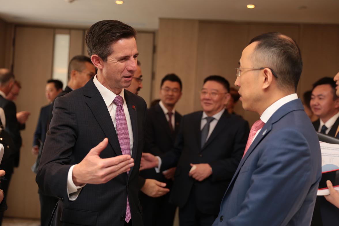 Trade, Tourism and Investment Minister Simon Birmingham speaking with Mengniu President Lu Jeffrey. People in the background.